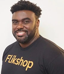 Marcus Bullock smiling in a Flikshop shirt against a plain background