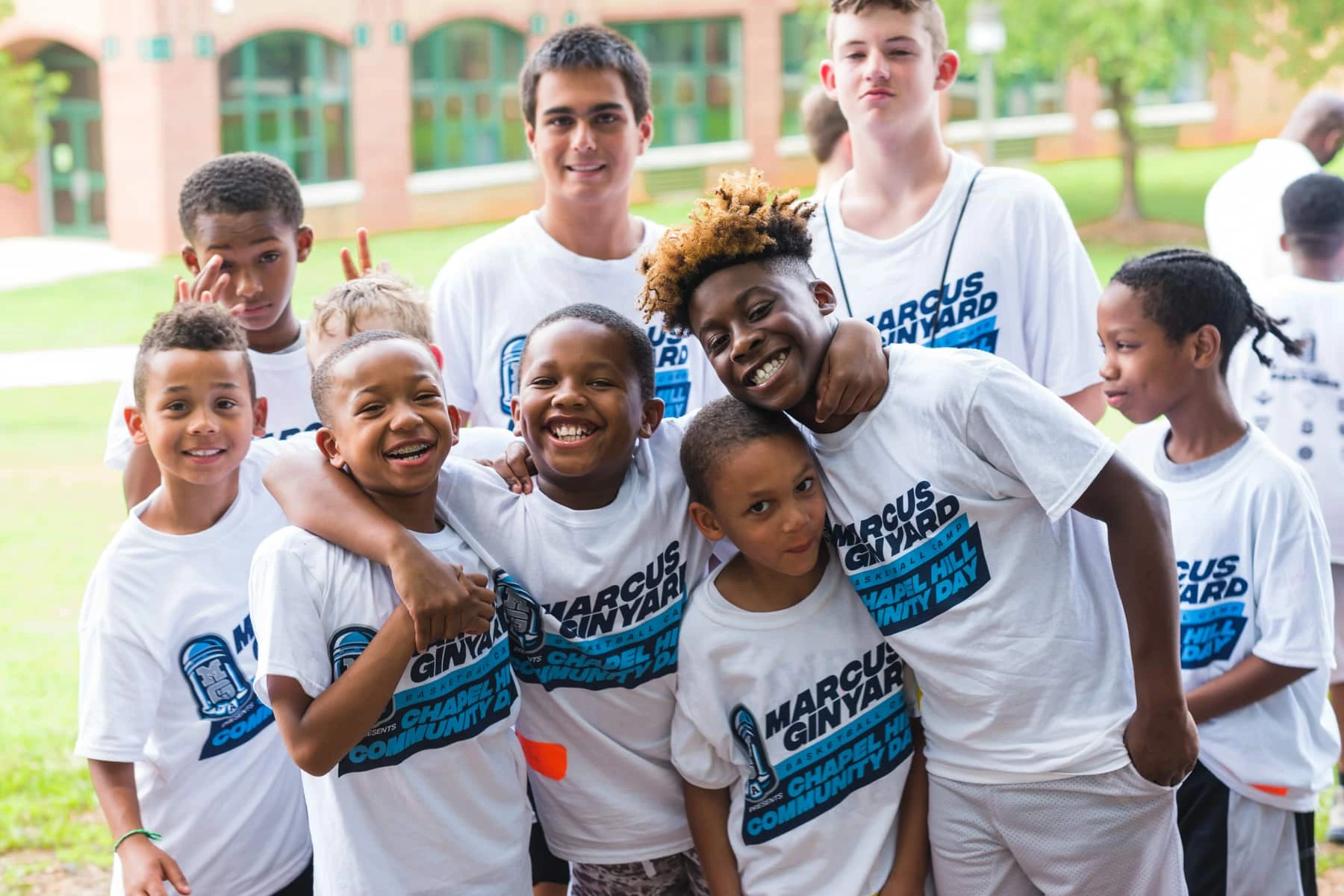 Marcus Ginyard posing with children at a basketball camp event